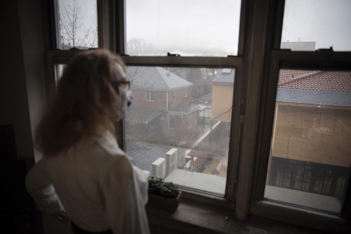 FILE - In this Thursday, March 18, 2021 file photo, Bonney Ginett looks out the window of her apartment in the Queens borough of New York. Ginett, whose massage therapy business dried up during the pandemic, applied for help in July and said she was denied in October because she failed to prove loss of income. The 65-year-old New York City resident now owes more than $26,000 in back rent on her one-bedroom apartment and fears eviction.