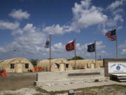 FILE - In this April 18, 2019, file photo, in this photo reviewed by U.S. military officials, flags fly in front of the tents of Camp Justice in Guantanamo Bay Naval Base, Cuba.