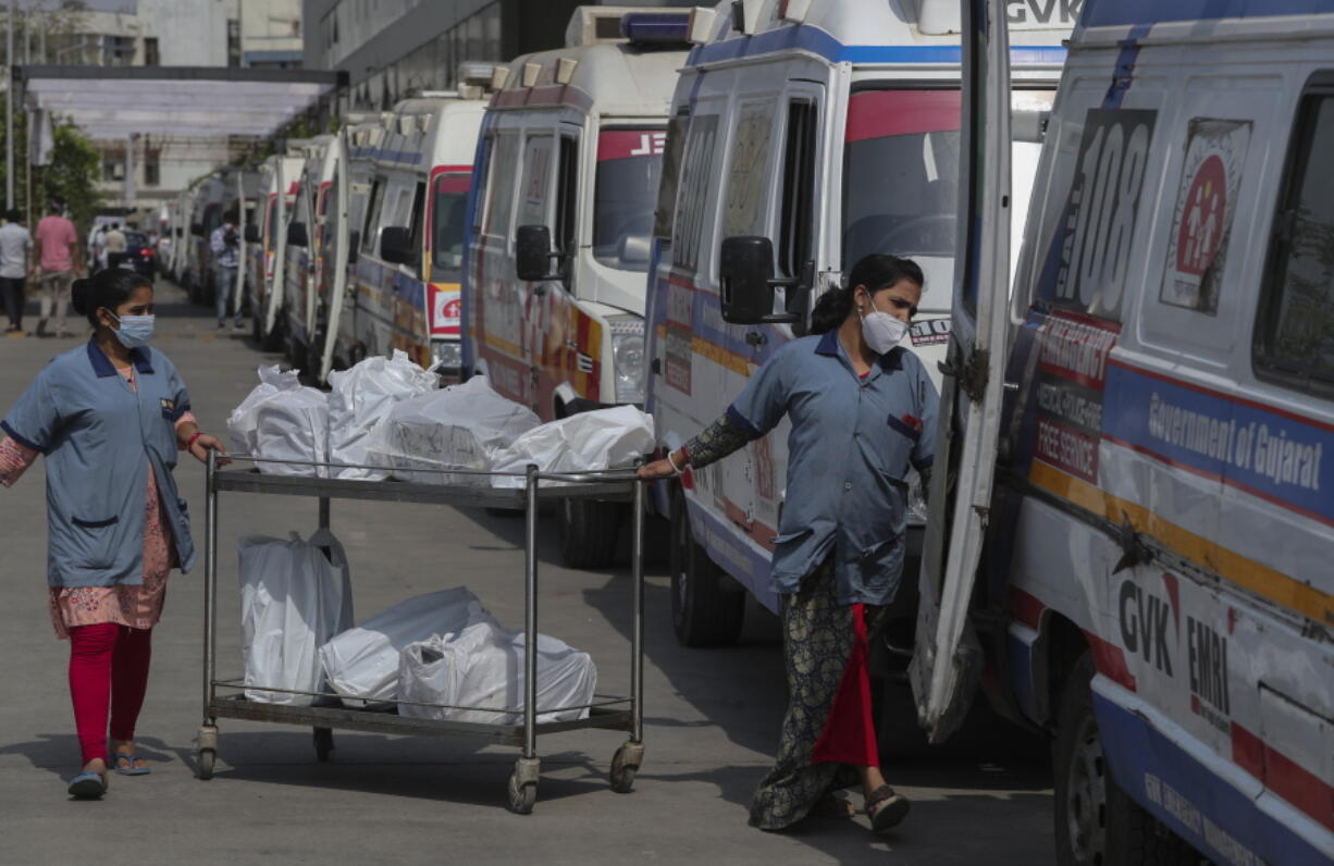 Hospital staff distribute food packets to the staff of ambulances carrying COVID-19 patients and their relatives as they queue up waiting for their turn to be attended at a government COVID-19 hospital in Ahmedabad, India, Tuesday, April 27, 2021. The COVID-19 death toll in India has topped 200,000 as the country endures its darkest chapter of the pandemic yet.