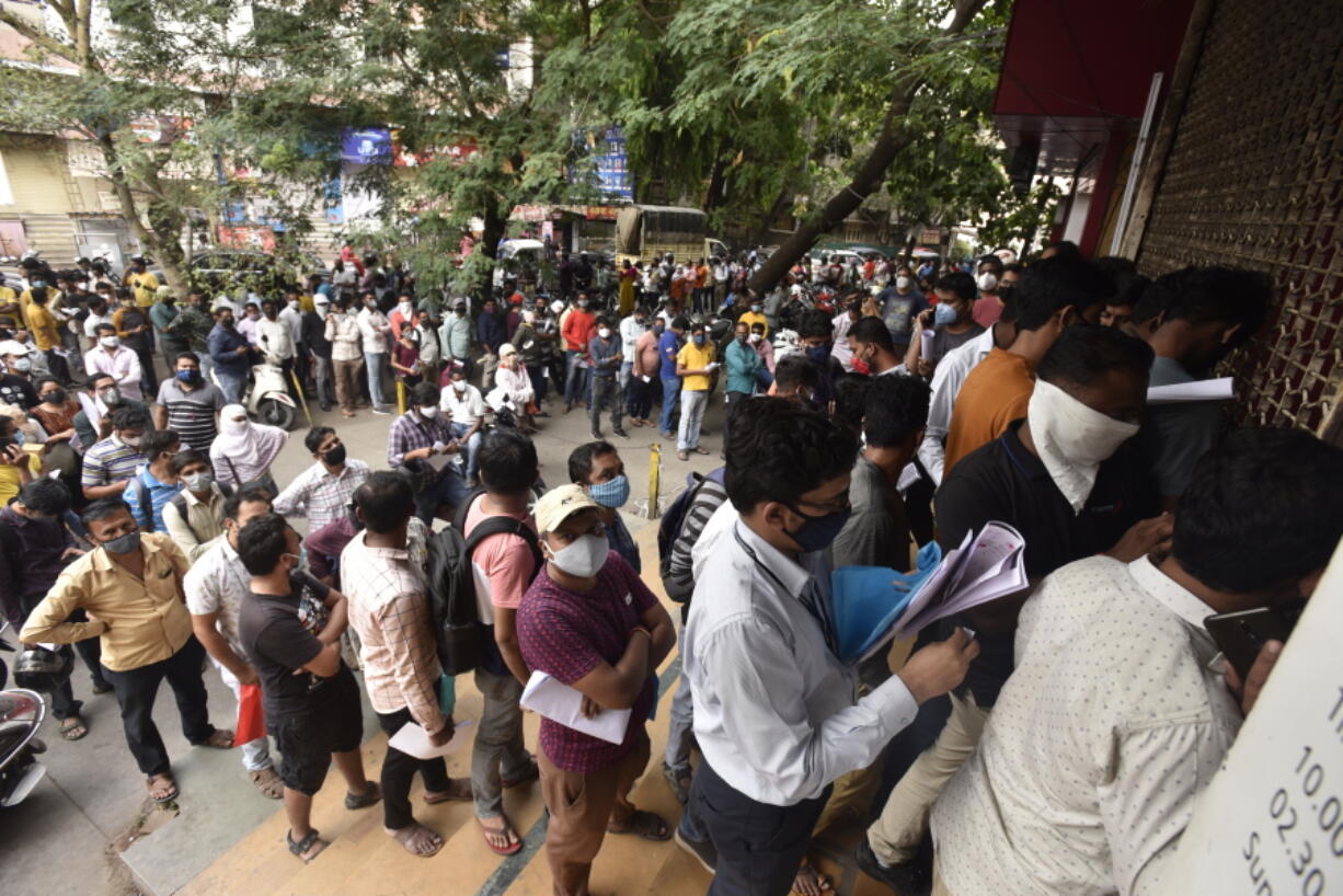 People wait in queues outside the office of the Chemists Association to demand necessary supply of the anti-viral drug Remdesivir, in Pune, India, Thursday, April 8, 2021. India is amid its worst pandemic surge,  with over 100,000 cases in the past 24 hours.