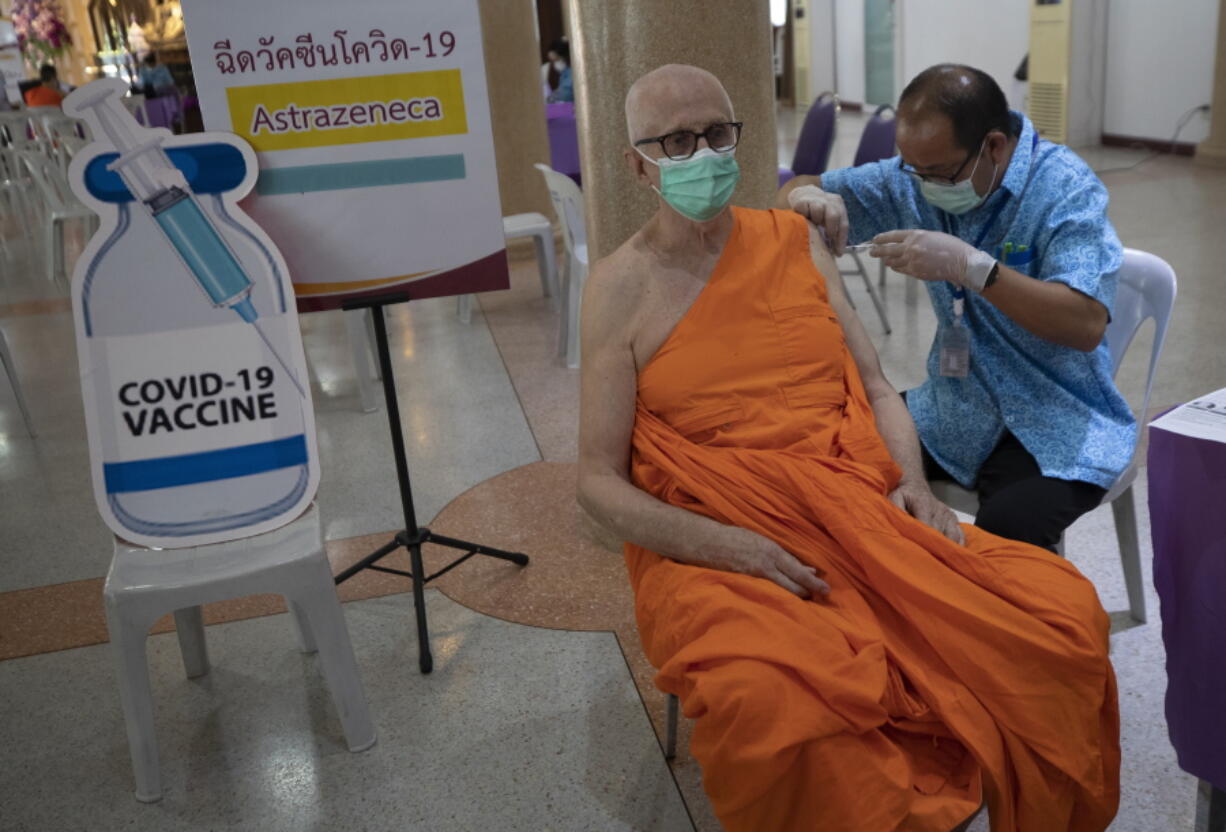 A health worker administers a dose of the AstraZeneca COVID-19 vaccine to a Buddhist monk at Nak Prok Temple in Bangkok, Thailand, Friday, April 9, 2021.