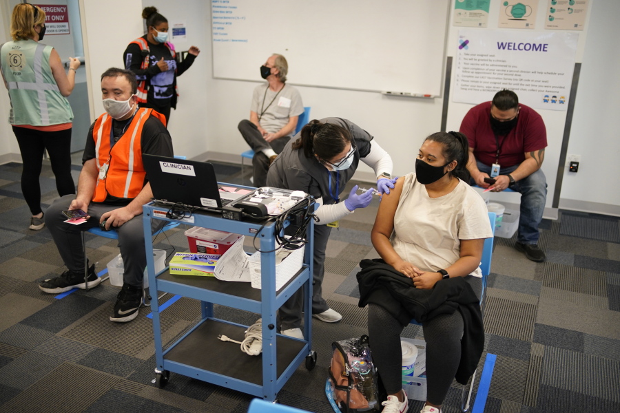 Registered nurse Rocio Ortiz administers a vaccine shot at a vaccination event for workers at an Amazon Fulfillment Center, Wednesday, March 31, 2021, in North Las Vegas, Nev. A growing number of companies and labor unions are directly securing coronavirus vaccines for their workers. Amazon and some other large companies have hosted on-site inoculations, while smaller operations have helped book appointments for their workers.