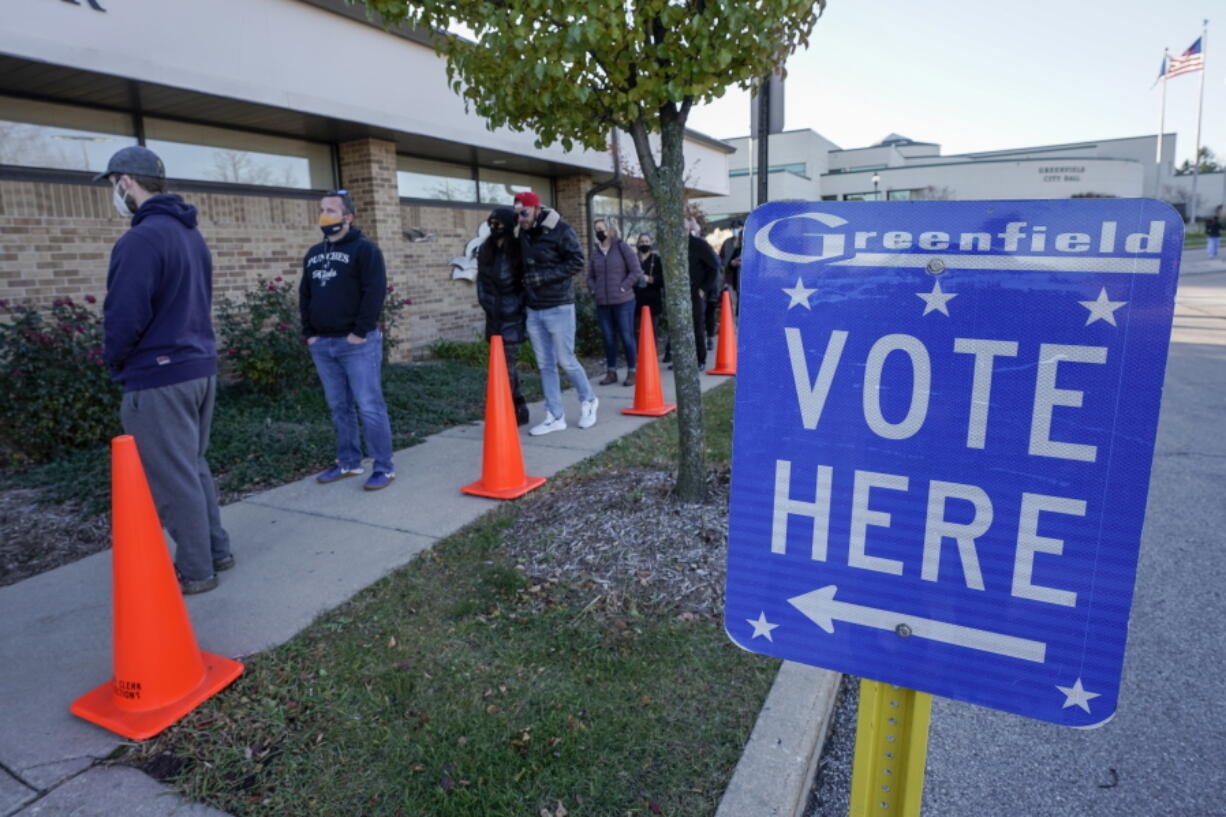 FILE- In this Nov. 3, 2020, file photo people line up to vote outside the Greenfield Community Center on Election Day in Greenfield, Wis. The Wisconsin Supreme Court sided with Democrats on Friday, April 9, 2020, and ruled that the state elections commission should not remove from the rolls voters flagged as possibly having moved, something conservatives have wanted done for nearly two years.