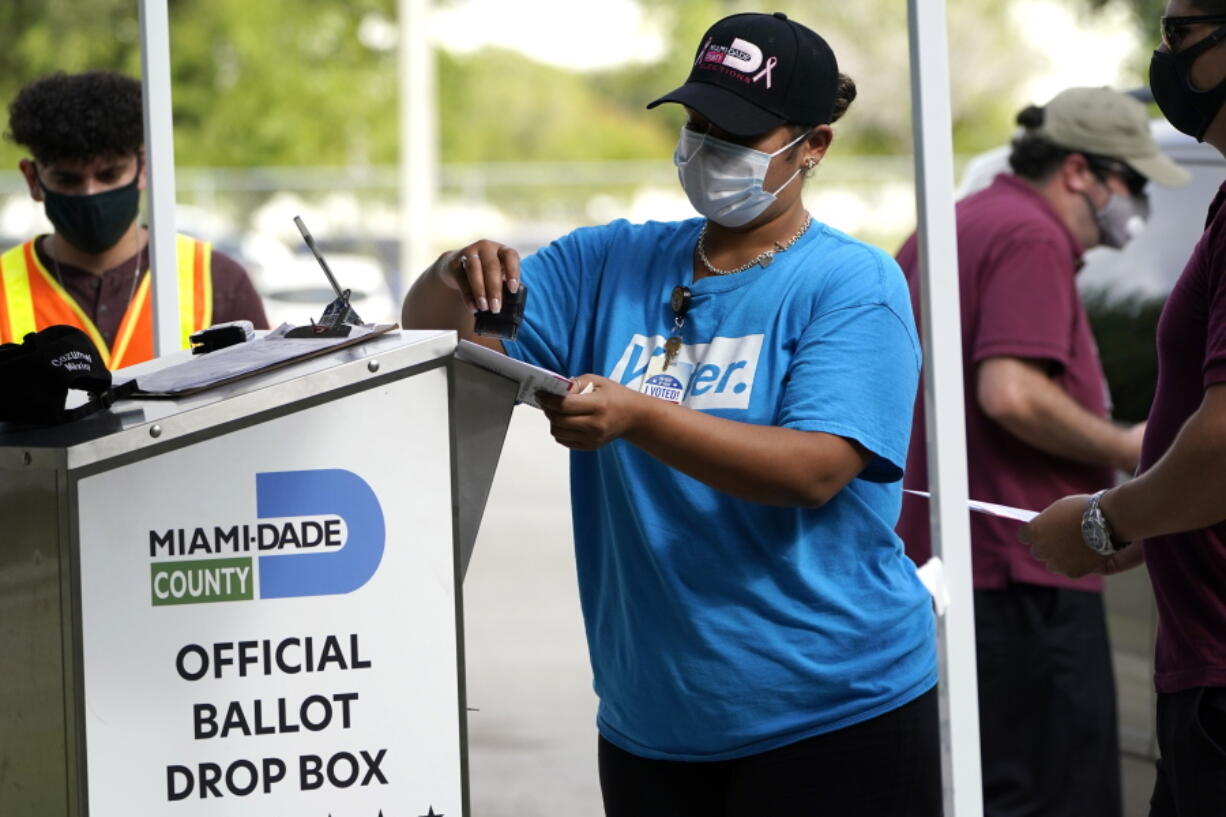 FILE - In this Monday, Oct. 26, 2020, file photo, an election worker stamps a vote-by-mail ballot dropped off by a voter before placing it in an official ballot drop box before at the Miami-Dade County Board of Elections in Doral, Fla. Ballot drop boxes were enormously popular during the 2020 election, with few problems reported. Yet they have drawn the attention of Republican lawmakers in key states who say security concerns warrant new restrictions.