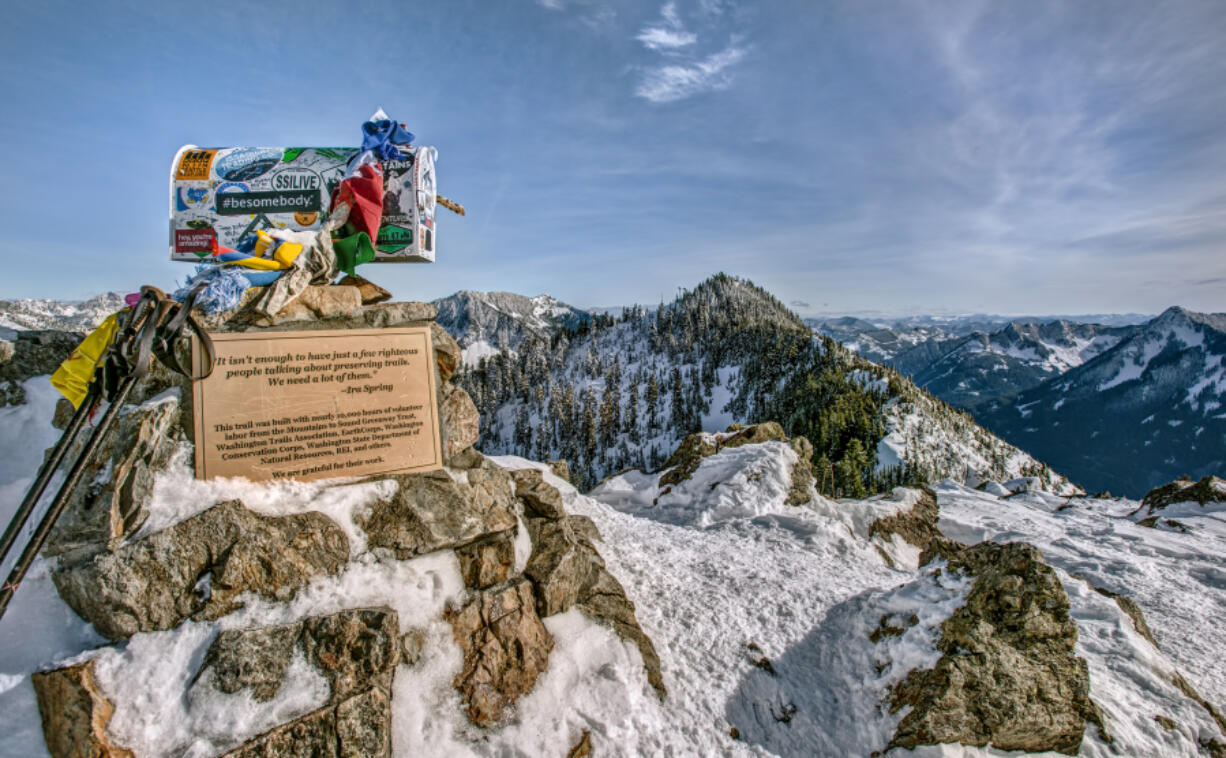 A Mailbox and Trekking Poles mark the Snowy Summit of Mailbox Peak in the Cascade Mountain Range.