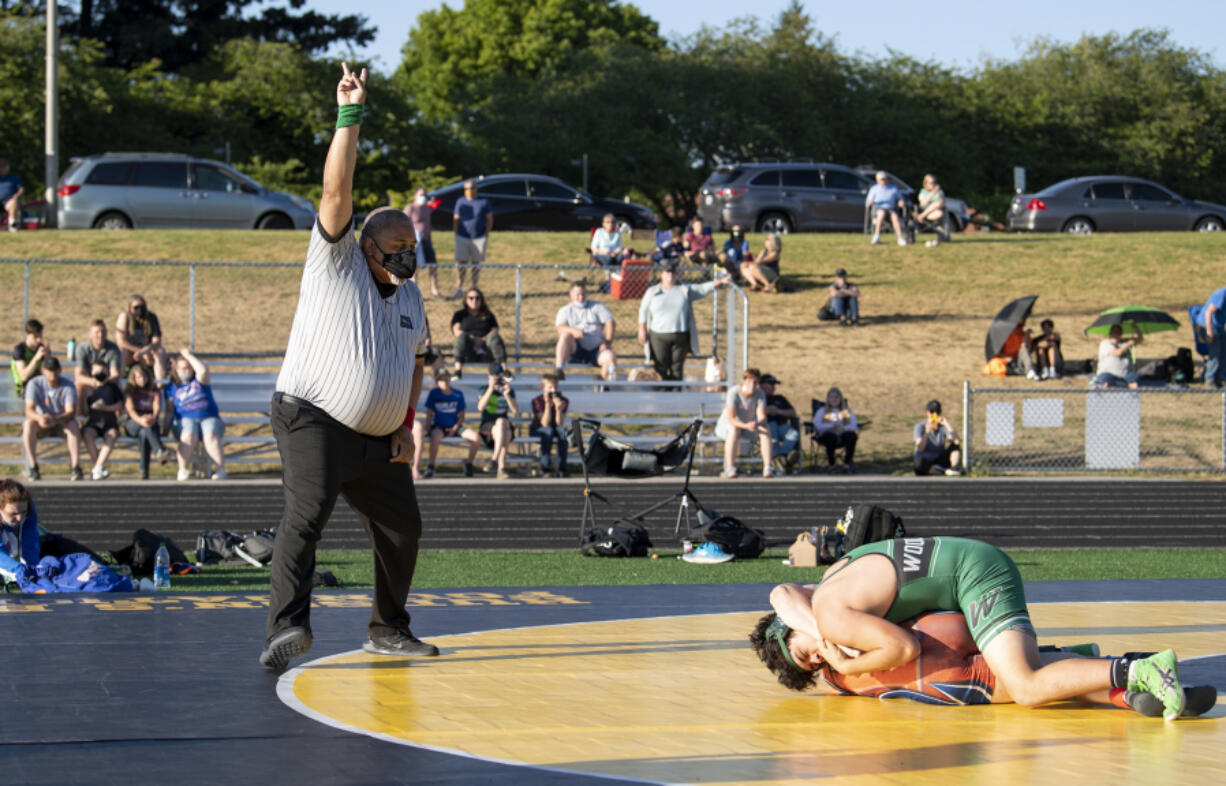 Washington Officials Association referee Lee Lofton calls two points for a takedown on Wednesday at Hudson's Bay High School. The dual meet between Woodland, Ridgefield and Hudson's Bay was believed by coaches to be among the first outdoor dual meets held in state history.