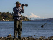 Peter Cavanagh is an award-winning wildlife photographer and a retired University of Washington professor who lectures on the mathematics of bird flight. Behind Cavanagh is great blue heron, on April 15, 2021, at West Point Light House Beach in Seattle's Discovery Park.