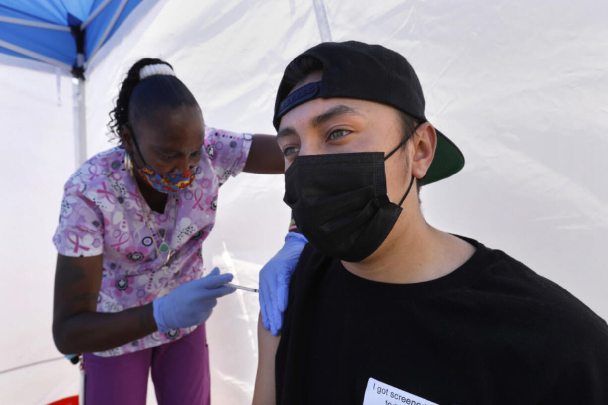 Tanya Mitchell, a certified medical assistant, left, administers his a vaccinate to Richard Ayala, age 18, at the East Los Angeles Civic Center on May 12, 2021.