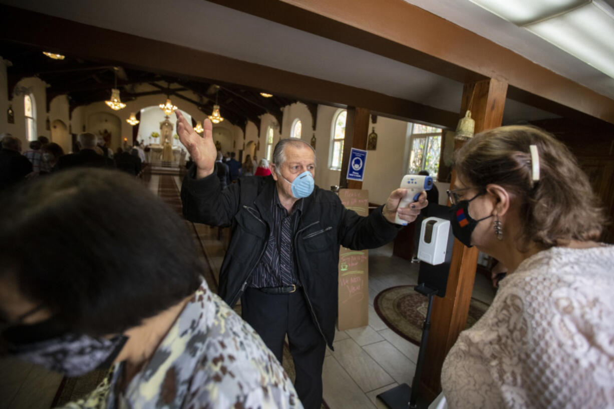 Usher Antoine Soumakian takes parishioners temperatures as they file in for Sunday service at Our Lady Queen of Martyrs Church, an Armenian church on Sunday, April 25, 2021 in Boyle Heights, CA.