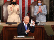 U.S. President Joe Biden removes his face mask before addressing a joint session of Congress as Vice President Kamala Harris, left, and Speaker of the House U.S. Rep. Nancy Pelosi (D-CA) look on in the House chamber of the U.S. Capitol April 28, 2021 in Washington, DC.