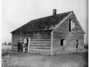 About 1920, two men in business-like dress stand near the doorway of the decaying Covington House at its original Orchards site on Covington Road. The Clark County Historical Society (then the Fort Vancouver Historical Society) and the Vancouver Women's Club planned on moving the cabin log by log in 1926 and rebuilt it about 1928 at today's location on Main Street near the Kiggins Bowl.