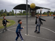 Kindergartners Makhari Lang, from left, Anthony Miller and Zephaniah Keli Aitu test their tetherball skills during recess at Eisenhower Elementary School on Monday. Vancouver Public Schools expanded in-person instruction for four grades and plans to expand to another four grades next week.