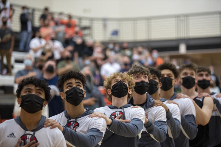 Members of the Union High School boys basketball team look to the American flag as the National Anthem plays before their win against Battle Ground High School on Tuesday night, May 11, 2021.