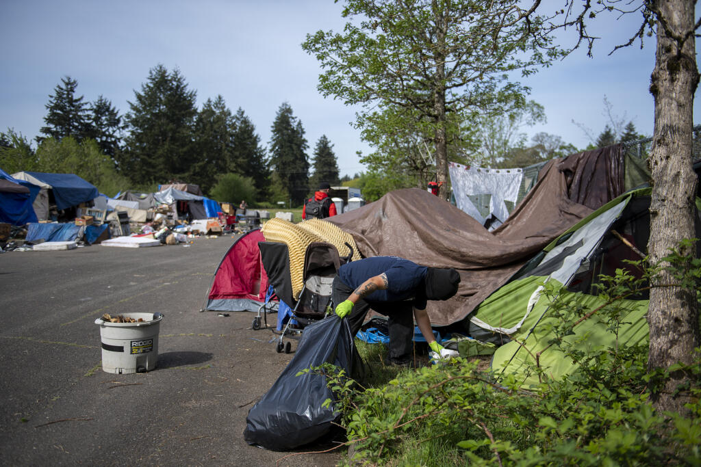 A worker removes garbage from a homeless encampment in northeast Vancouver on Thursday morning, April 29, 2021. Vancouver's new homeless resources coordinator is presenting her strategy for supported camp sites.