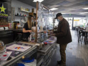 Alisha Heilman serves customer Roger Keast of Vancouver on Friday morning at Madhouse Coffee in Vancouver.