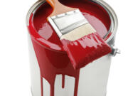 paint bucket with red paint and brush on white background.