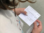 Jane Ellen Norman, 12, holds vaccination cards for her and her 14-year-old brother Owen outside Mercedes-Benz Stadium in Atlanta on Tuesday, May 11, 2021. The two were vaccinated Tuesday morning, after U.S. regulators expanded use of Pfizer's COVID-19 shot to those as young as 12.