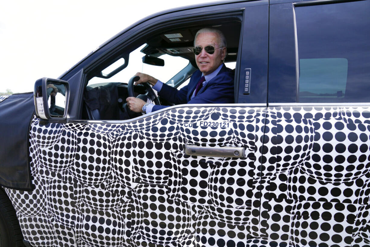 President Joe Biden stops to talk to the media as he drives a Ford F-150 Lightning truck at Ford Dearborn Development Center, Tuesday, May 18, 2021, in Dearborn, Mich.