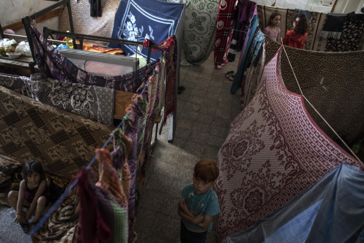 Palestinians take shelter at a school run by the U.N. after fleeing heavy Israeli missile strikes in the outskirts of Gaza City, Wednesday, May 19, 2021. The Gaza Strip's already feeble health system is being brought to its knees by the fourth war in just over a decade. At the school, no one wore a mask or could do any social distancing in the cramped quarters.