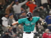 Seattle Mariners' Jarred Kelenic reacts to the home run of Mitch Haniger as he heads in to score against the Cleveland Indians during the seventh inning of a baseball game Friday, May 14, 2021, in Seattle.