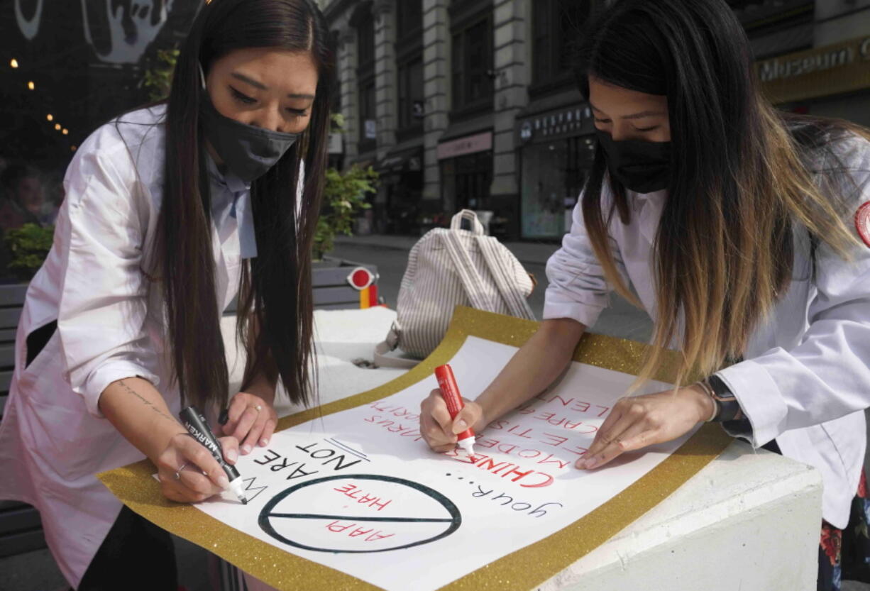 Dr. Michelle Lee, left, a radiology resident, and Ida Chen, right, a physician assistant student, prepare posters they carry at rallies protesting anti-Asian hate, Saturday April 24, 2021, in New York's Chinatown. Lee, who is Korean-born, and Chen, who is American-born Chinese, join medical professionals of Asian and Pacific Island descent who feel the anguish of being racially targeted because of the virus while toiling to keep people from dying of it.