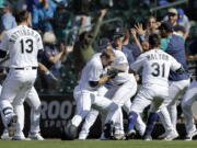 Seattle Mariners players surround Tom Murphy, center, after he hit a sacrifice fly, scoring the winning run, in the 10th inning against the Oakland Athletics on Monday in Seattle. The Mariners won their fifth straight game and improved to 5-0 in extra innings.