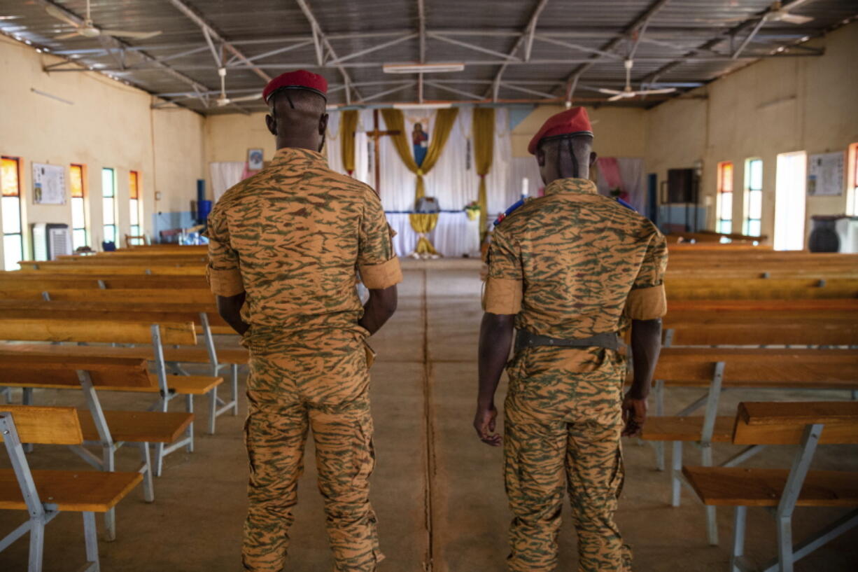 Two soldiers stand in the Catholic church at the 10th RCAS army barracks in Kaya, Burkina Faso, Saturday, April 10, 2021. Once considered a beacon of peace and religious coexistence in the region, the West African nation has been embroiled in unprecedented violence linked to al-Qaida and the Islamic State since 2016, throwing an ill-equipped and undertrained army into disarray - and overwhelming the chaplains tasked with supporting them.