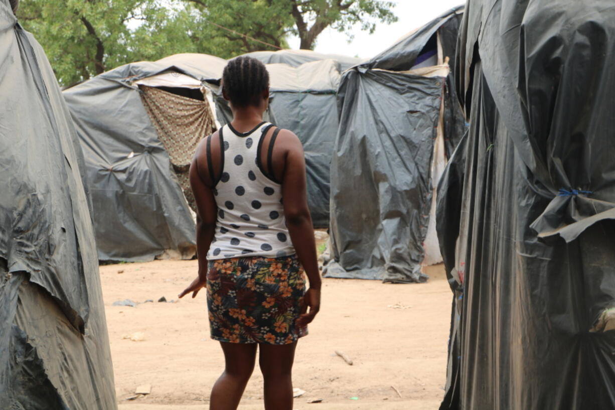 A woman who said she was trafficked from Nigeria under false pretenses to work as a sex slave in Burkina Faso's mining sites, walks through a row of tent in the Secaco mining town June 12, 2020. As part of a months-long investigation into sex trafficking and the gold mining industry, The Associated Press met with nearly 20 Nigerian women who said they had been brought to Burkina Faso under false pretenses, then forced into prostitution.