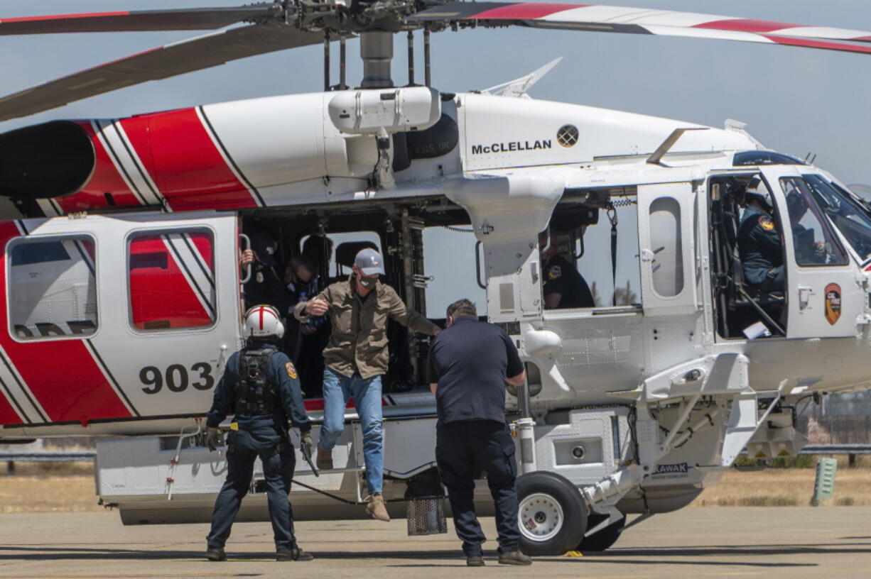 California Gov. Gavin Newsom jumps out of a new Sikorsky S70i Black Hawk firefighting helicopter after arriving to highlight new firefighting equipment and his proposed $2 billion investment in wildfire and emergency preparedness at a press conference in McClellan Park in Sacramento County on Monday, May 24, 2021. (Renee C.