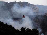 A firefighting helicopter prepares to drop water onto a wildfire in the Pacific Palisades area of Los Angeles, Sunday, May 16, 2021. (AP Photo/Ringo H.W.