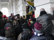 FILE - In this Jan. 6, 2021 file photo insurrectionists loyal to President Donald Trump try to open a door of the U.S. Capitol as they riot in Washington. With riot cases flooding into Washington's federal court, the Justice Department is under pressure to quickly resolve the least serious cases.