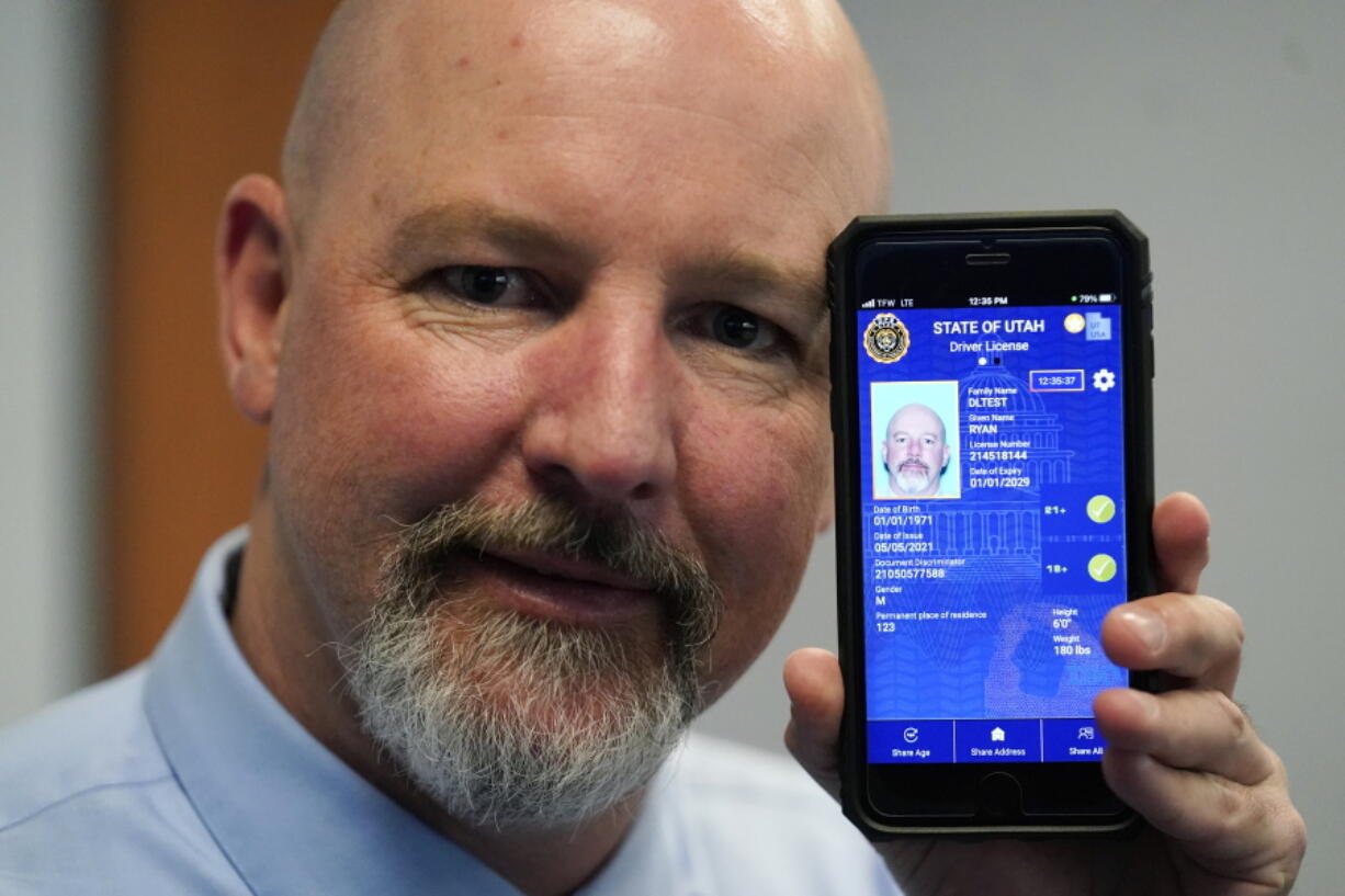 Ryan Williams, with the Utah Drivers License Division, displayes his cell phone with the pilot version of the state's mobile ID on Wednesday, May 5, 2021, in West Valley City, Utah. The card that millions of people use to prove their identity to everyone from police officers to liquor store owners may soon be a thing of the past as a growing number of states develop digital driver's licenses. In Utah, over 100 people have a pilot version of the state's mobile ID, and that number is expected to grow to 10,000 by year's end. Widespread production is expected to begin at the start of 2022.