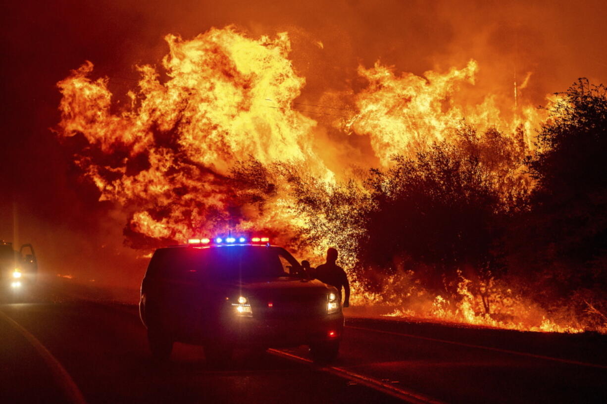 Flames rise above vehicles Sept. 9, 2020, on Highway 162 during the Bear Fire in Oroville, Calif. Scientists say the outlook for the western U.S. fire season is grim because it's starting drier than 2020's record-breaking fire year.