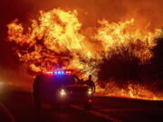 Flames rise above vehicles Sept. 9, 2020, on Highway 162 during the Bear Fire in Oroville, Calif. Scientists say the outlook for the western U.S. fire season is grim because it's starting drier than 2020's record-breaking fire year.