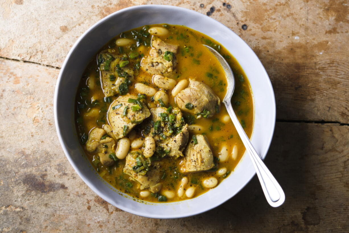 This image released by Milk Street shows a recipe for cardamom lime chicken with white beans.