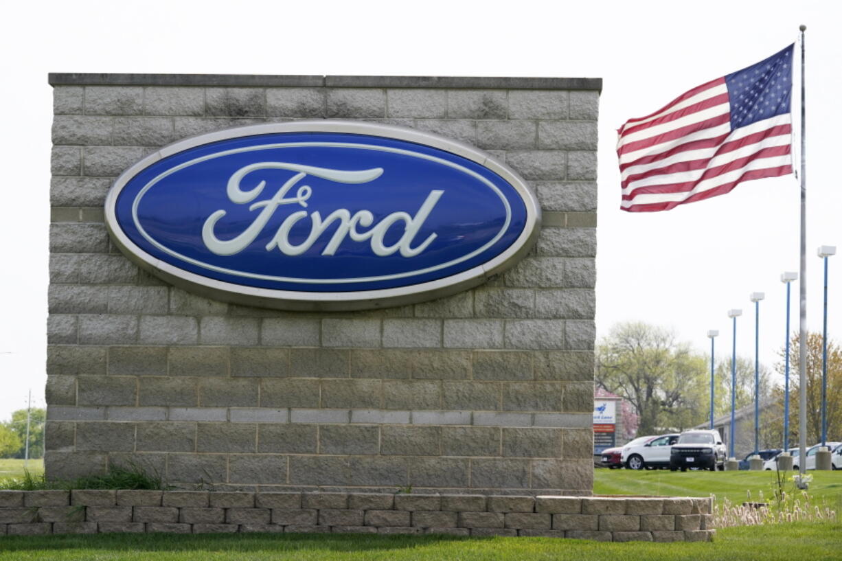 FILE - In this April 27, 2021 file photo, an American flag flies over a Ford auto dealership, in Waukee, Iowa. Ford says it expects 40% of its global sales to be battery-electric vehicles by 2030 as it adds billions to the amount its spending to develop them. Ahead of a presentation to Wall Street on Wednesday morning, May 26 the automaker says it will add about $8 billion to its EV development spending from this year to 2025.