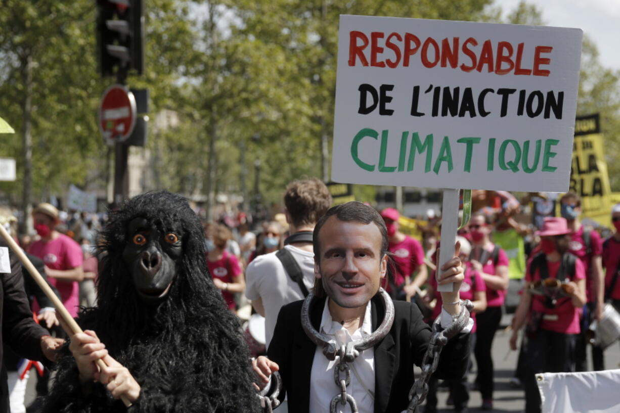 A protester wearing a mask depicting French President Emmanuel Macron holds a bord reading << Liable for climate inaction >> during a rally against the climate change in Paris, Sunday, May 9, 2021. Thousands of French demonstrators took to the streets of Paris and other cities on Sunday to call for more ambitious measures to fight against climate change.