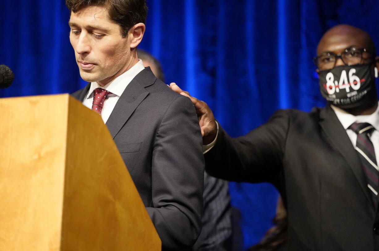 FILE - In this March 12, 2021, file photo, Philonise Floyd, George's brother, placed his hand on the shoulder of Minneapolis mayor Jacob Frey as Frey walked to the podium to speak during a press conference to announce a $27 million civil lawsuit settlement between the Floyd family and the City of Minneapolis, in Minneapolis. From COVID-19 to a budget shortfall, and from the death of George Floyd to the more recent death of a 6-year-old girl from gun violence, the mayor of Minneapolis says his city has experienced one trauma after another in the last year '?? and the city's Black community has felt the pain the most.