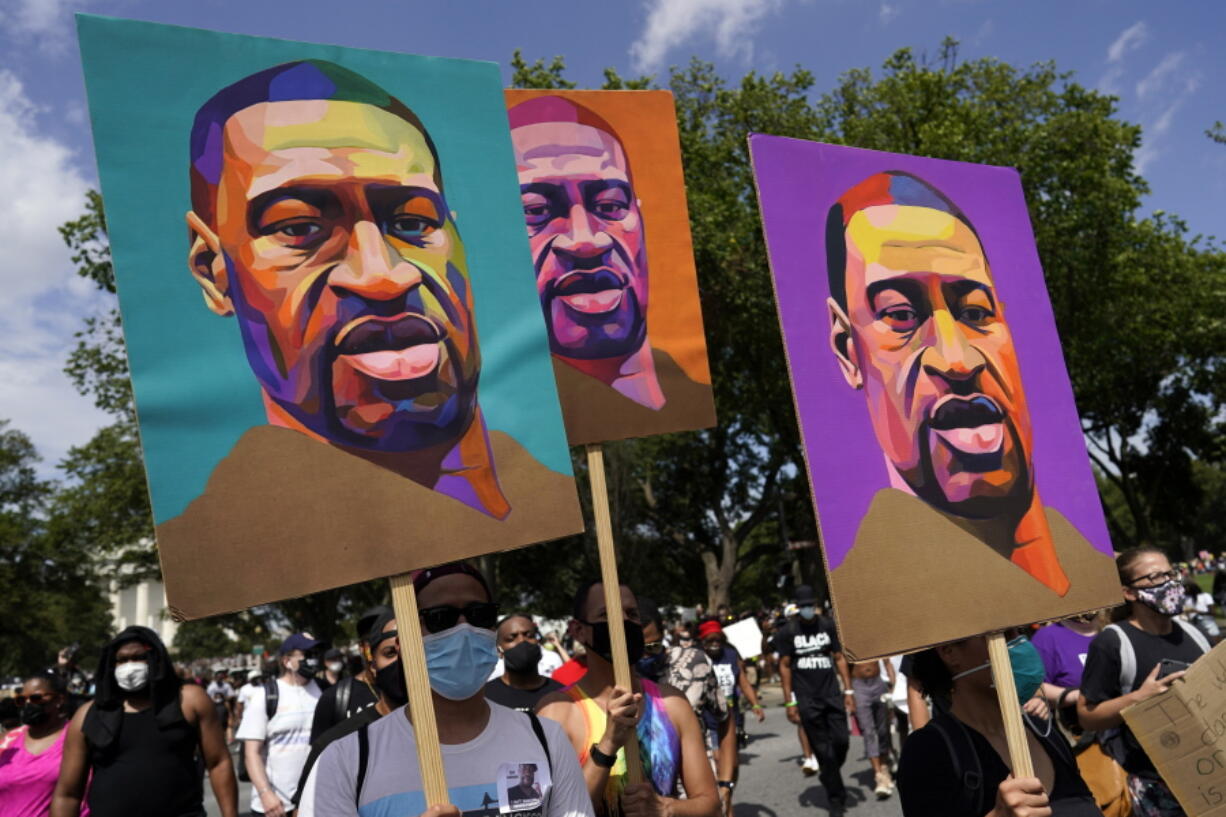 FILE - In this Aug. 28, 2020, file photo, people carry posters with George Floyd on them as they march from the Lincoln Memorial to the Martin Luther King Jr. Memorial in Washington. As the anniversary of George Floyd's murder approaches, some people say the best way to honor him is for Congress to pass a bill in his name that overhauls policing.