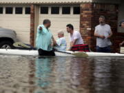 FILE - In this Aug. 27, 2017 file photo, people walk through floodwaters in Houston, Texas. The remnants of Hurricane Harvey sent devastating floods pouring into Houston. Houston area officials expressed shock and anger on Friday, May 21, 2021, after learning that their communities, which suffered the brunt of damage from Hurricane Harvey, would be getting a fraction of $1 billion that Texas is awarding as part of an initial distribution of federal funding given to the state for flood mitigation.