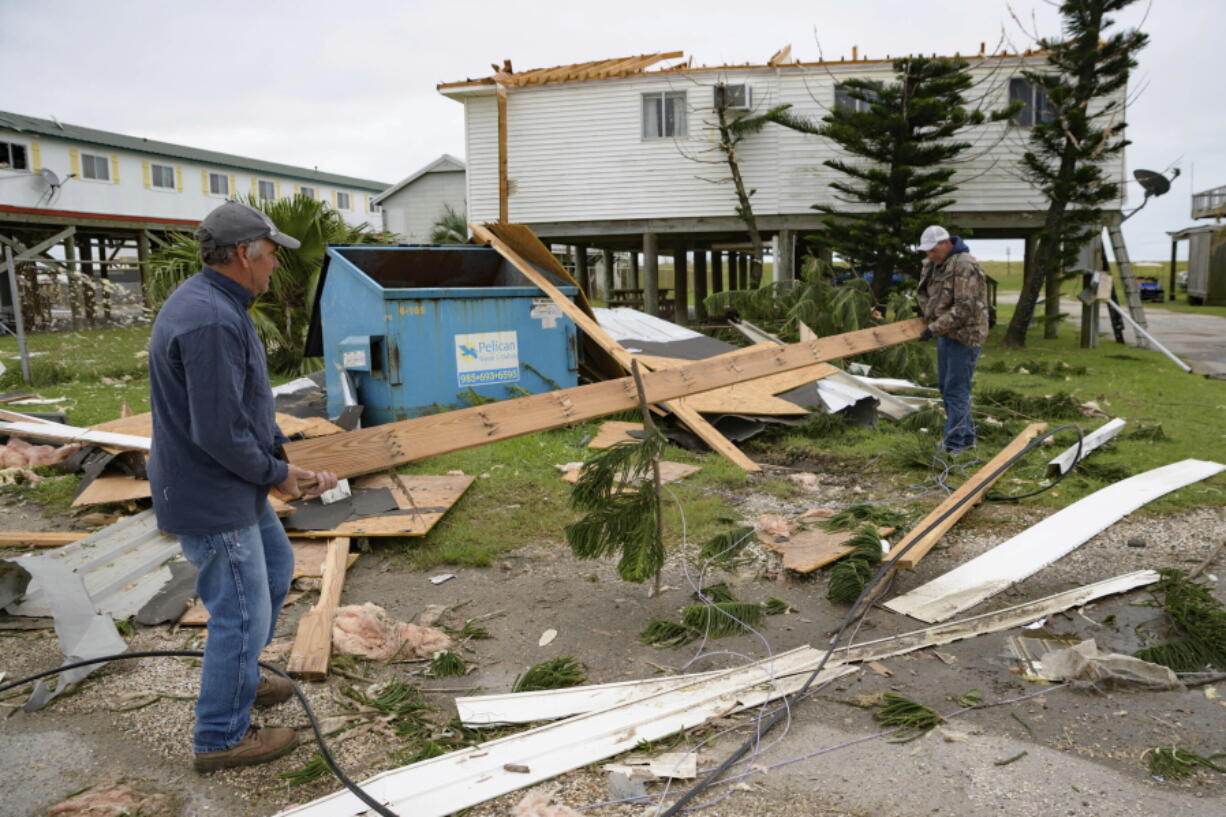 Mark Andollina, left, and Shane Holder clean debris left by Hurricane Zeta at the Cajun Tide Beach Resort in Grand Isle, La., on Oct. 30. The hurricane has been upgraded to a major, Category 3 storm.