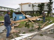 Mark Andollina, left, and Shane Holder clean debris left by Hurricane Zeta at the Cajun Tide Beach Resort in Grand Isle, La., on Oct. 30. The hurricane has been upgraded to a major, Category 3 storm.