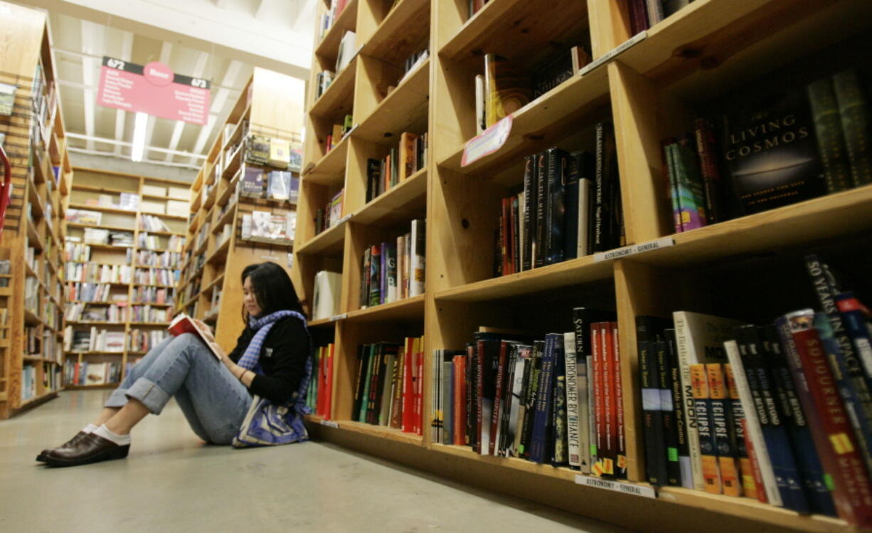 FILE - A woman reads a book in Powell's Bookstore in downtown Portland, Ore., on, Jan. 4, 2008. On Thursday, the American Booksellers Association said that membership increased from 1,635 to 1,701 since May 2020, the additions a combination of brand new stores and existing stores that had not previously been part of the independents' trade group. While association CEO Allison Hill and others had feared that hundreds of stores could go out of business during the 2020-21 holiday season, the ABA so far has only tallied 14 closings in 2021, along with more than 70 last year.