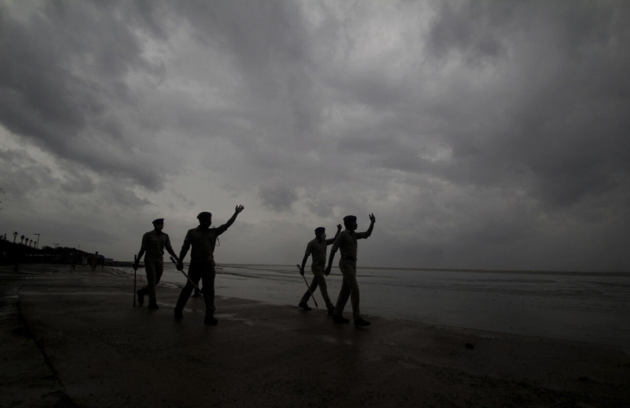 Policemen ask people to move to cyclone shelters as they patrol a beach in Balasore district in Odisha, India, Tuesday, May 25, 2021. Tens of thousands of people were evacuated Tuesday in low-lying areas of two Indian states and moved to cyclone shelters to escape a powerful storm barreling toward the eastern coast.