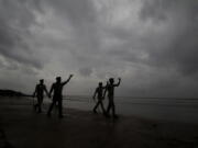 Policemen ask people to move to cyclone shelters as they patrol a beach in Balasore district in Odisha, India, Tuesday, May 25, 2021. Tens of thousands of people were evacuated Tuesday in low-lying areas of two Indian states and moved to cyclone shelters to escape a powerful storm barreling toward the eastern coast.