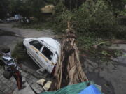 A car stands damaged with a fallen tree after heavy rainfall in Mumbai India, Tuesday, May 18, 2021. The Maharashtra state capital was largely spared from any major damage as Cyclone Tauktae, the most powerful storm to hit the region in more than two decades, came ashore in neighboring Gujarat state late Monday.