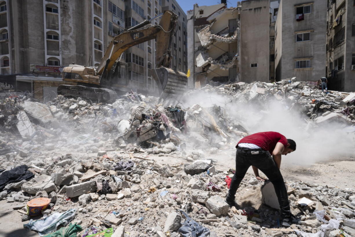 Heavy construction equipment is used to sift through rubble to uncover valuables before it is transported away from the scene of a building destroyed in an airstrike prior to a cease-fire that halted an 11-day war between Gaza's Hamas rulers and Israel, Thursday, May 27, 2021, in Gaza City.