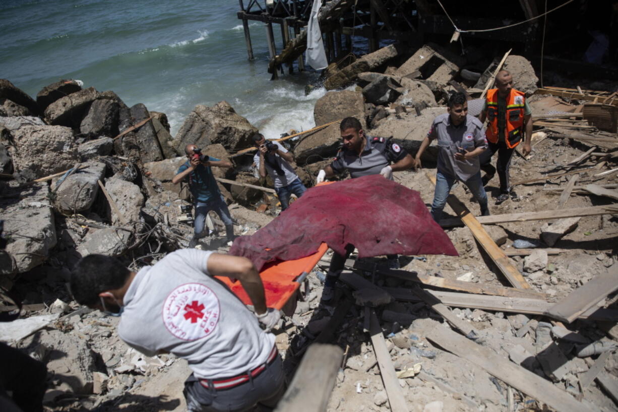 Palestinian rescue workers carry the remains of a man found next to a beachside cafe after it was hit by an Israeli airstrike, in Gaza City, Monday, May 17, 2021.