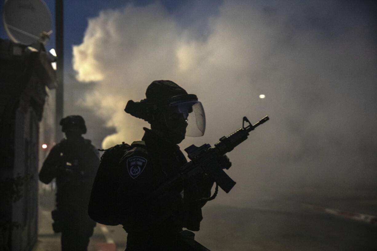 Israeli forces run during clashes with Israeli Arabs in the Israeli mixed city of Lod, Israel, Tuesday, May 11,2021.