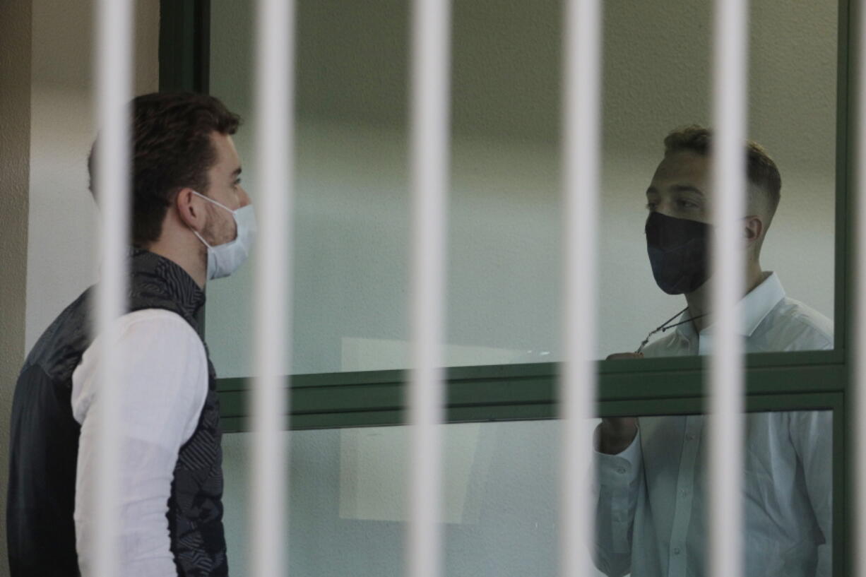 Finnegan Lee Elder, right, shows a crucifix to co-defendant Gabriel Natale-Hjorth before a jury began deliberating their fate in their trial for the slaying of an Italian plainclothes police officer on a street near the hotel where they were staying while on vacation in Rome in summer 2019, in Rome, Wednesday, May 5, 2021.